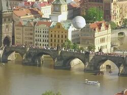 WS AERIAL PAN View of pedestrians walking on bridge over river to air balloon over church / Prague, Czech Republic Stock Footage