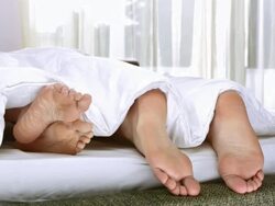HD DOLLY: Couple's Feet Playing In Bed Stock Footage