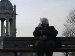 Old woman sitting on a bench, winter Stock Footage