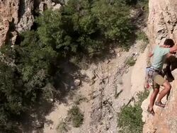 Handheld shot of a rock-climber climbing a jagged cliff. Stock Footage