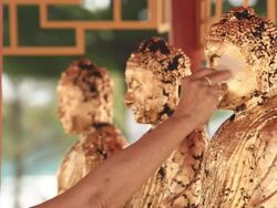 Putting Gold Leaf On Buddha Statue Stock Footage