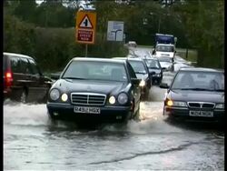 MS zooming out to MWA, Queue of cars driving slowly through flooded road, white cloudy sky, UK Stock Footage