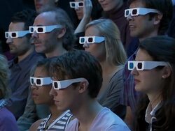 Medium shot audience wearing 3-D glasses reacting to movie out of frame with shock and pleasure Stock Footage