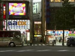 MS Shot of cars passing on street with neon signs and shops at night / Tokyo, Japan Stock Footage
