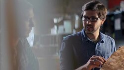 Wood shop craftsman points out design details of custom longboard to pupil Stock Footage