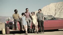 Group of friends lean on classic red convertible and laugh Stock Footage