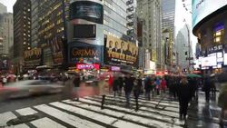 Pedestrians cross the intersection of 42nd Street in Times Square on a rainy day. Stock Footage