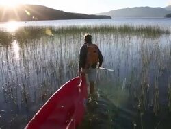 Man pulls kayak through marsh, then paddles, sunrise Stock Footage