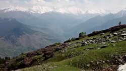Pan shot of rocks and field with Himalayan Mountains and dramatic clouds and sun rays across mountainous landscape. Stock Footage