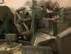Medium static - Factory machines spool silk thread above containers full of cocoons. / Malaysia Stock Footage