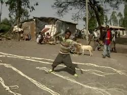 Ethiopian boy cracks whip at camel market Stock Footage