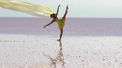 Young ballerina dancing on the salt lake with color tulle Stock Footage