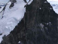'Medium Long Shot aerial tilt-down tracking-right-Snow blankets rugged glacial mountains in Alaska. / Alaska, USA' Stock Footage