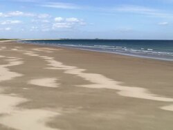 Aerial low over beach [toward Holy Island] on coast of Northumberland / England Stock Footage