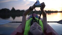 Woman using camera on kayak in twilight evening Stock Footage