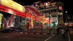 Pedestrians and traffic move past Chinese New Year Celebration decorations along New Bridge Road in Chinatown, Singapore. Stock Footage