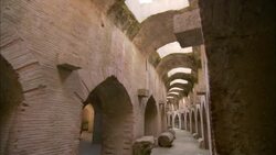 A corridor curves around archways below skylights in a Roman amphitheater. Stock Footage