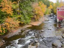 MS Shot of rapids on river by Power House Bridge in fall foliage in Northern New England / Johnson, Vermont, United States Stock Footage