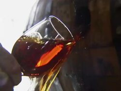 Close up of someone's hand filling a wine glass with bourbon flowing out of a barrel. Stock Footage