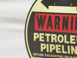 CU Sign of declaring Warning Petroleum Pipeline with reflections of nearby passing cars / Beaverton, Oregon, United States  Stock Footage