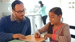 Father helping adolescent daughter with math assignment while homeschooling Stock Footage