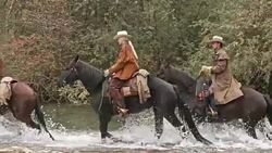 SLO MO Cowgirl and two cowboys riding horses across river Stock Footage