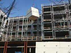 WS Crane moves large boxes in front of building being constructing / Detroit, Michigan, United States Stock Footage