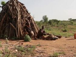 Woman and sun still in front of hut Stock Footage