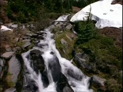 Waterfall in the mountains, white water flowing over rocks and boulders Stock Footage