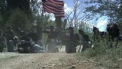 Union soldiers fire rifles on a dirt road near a wounded soldier in a Civil War reenactment. Stock Footage