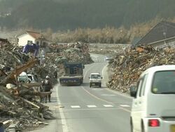Car drive along road bulldozed clear of deris through remains of Rikuzentakata city, Iwate Prefecture, Japan on 2nd April 2011; 3 weeks after the tsunami following the Tohuku earthquake of March 2011. Stock Footage