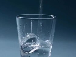 Water pouring into a glass of ice cubes  Stock Footage