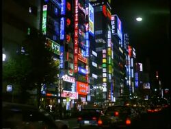 MWA traffic moving through city street, surrounded by High rise buildings and neon signs, at night, Shinjuku west district, Tokyo, Japan Stock Footage