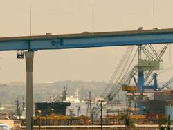 LS PAN traffic on Coronado Bridge near oil refinery and naval shipyard where battleship is under repair / San Diego, California, USA Stock Footage