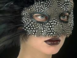 Close up of young woman in a feather mask turning to camera Stock Footage