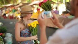 Cute girl poses for smartphone photo and twirls with bouquet of flowers in Brazilian public market Stock Footage
