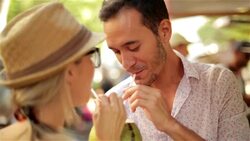 Young couple drink from coconut and kiss sweetly at sunny Rio outdoor market Stock Footage