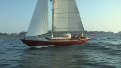 An American flag waves in the breeze behind a red sailboat as it sails across Narragansett Bay. Stock Footage
