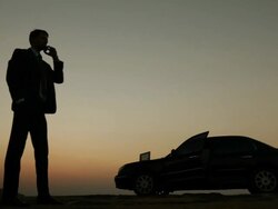 Silhouette of a businessman talking on a mobile phone and working on a laptop  Stock Footage