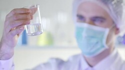 Scientist, doctor, student, in clean suit examining sample in test tube Stock Footage
