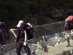 Travelers crossing a bridge over a river gorge in Nepal. Stock Footage