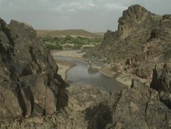 A high perspective of mountain rocks, looming over the meandering river below. Stock Footage
