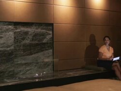  PAN Businesswoman sitting next to gas fireplace looking up from electronic tablet and smiling / Seattle, Washington, United States Stock Footage