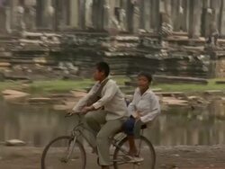 PAN TU Two boys on bicycle passing Bayon Temple at Angkor Thom / Angkor, Cambodia Stock Footage