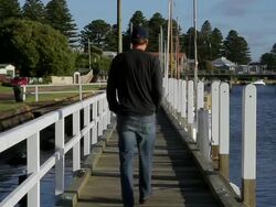 MS View of Man walking along Jetty on Moyne river in sleepy hamlet  / Port Fairy, Victoria, Australia Stock Footage