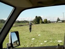 Father walking in field with son on shoulders in a field, viewed from inside a car Stock Footage