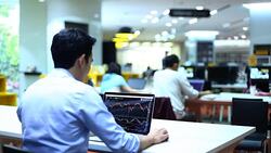 Business people using laptop and reviewing blueprints at desk Stock Footage
