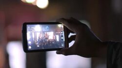 Man at rock concert taps smartphone touchscreen to focus image on band Stock Footage