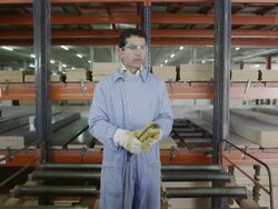 WS TS worker descending on retrieval lift in multi-story warehouse for pre-cut wood in furniture factory, front view Stock Footage