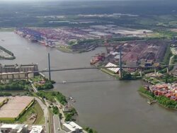 WS AERIAL View of running vehicles on suspension bridge and port near river with ship / Germany Stock Footage